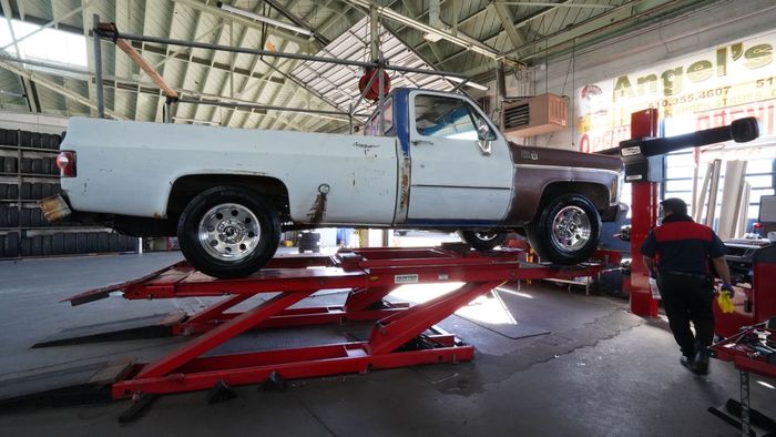White and brown pickup truck on a red lift inside an auto shop | Angel's Auto Repair And Service
