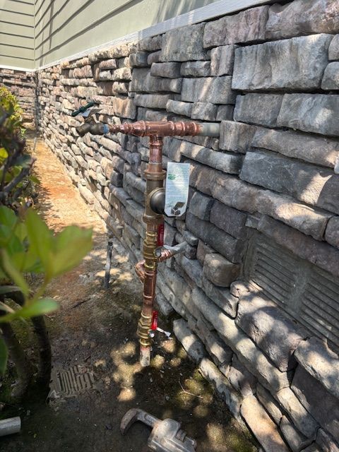 Copper pipes and valves attached to a stone wall.