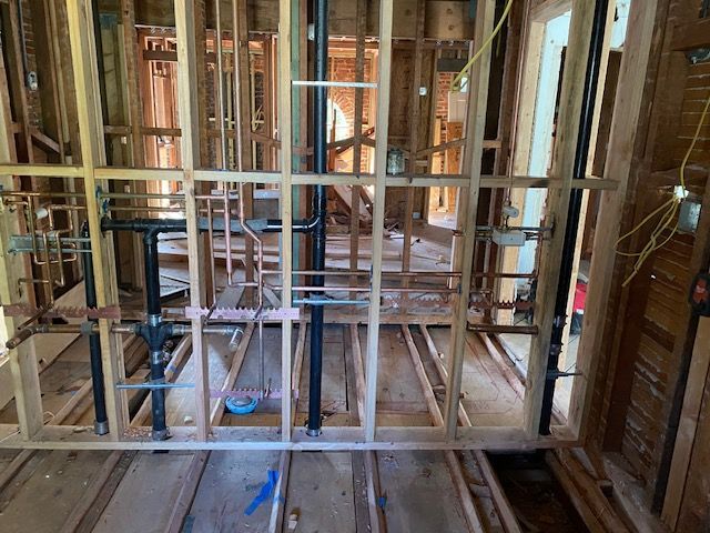 Interior framing with exposed plumbing and electrical wiring; construction site.