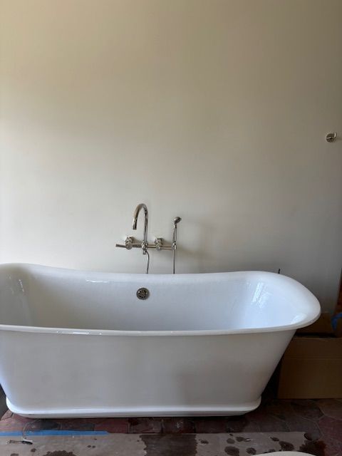 White claw-foot bathtub in front of a light-colored wall, with silver faucet and fixtures.