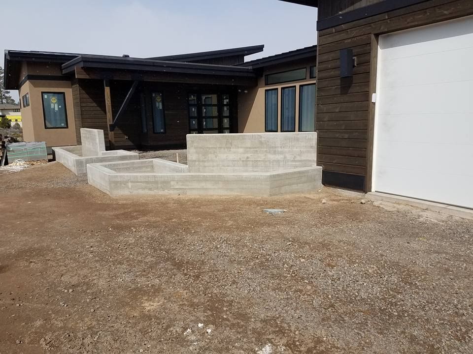 New home exterior with concrete steps, gravel yard, and a white garage door.