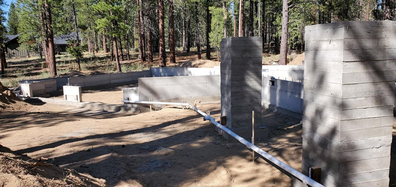 Construction site with concrete foundation and walls in a forest.