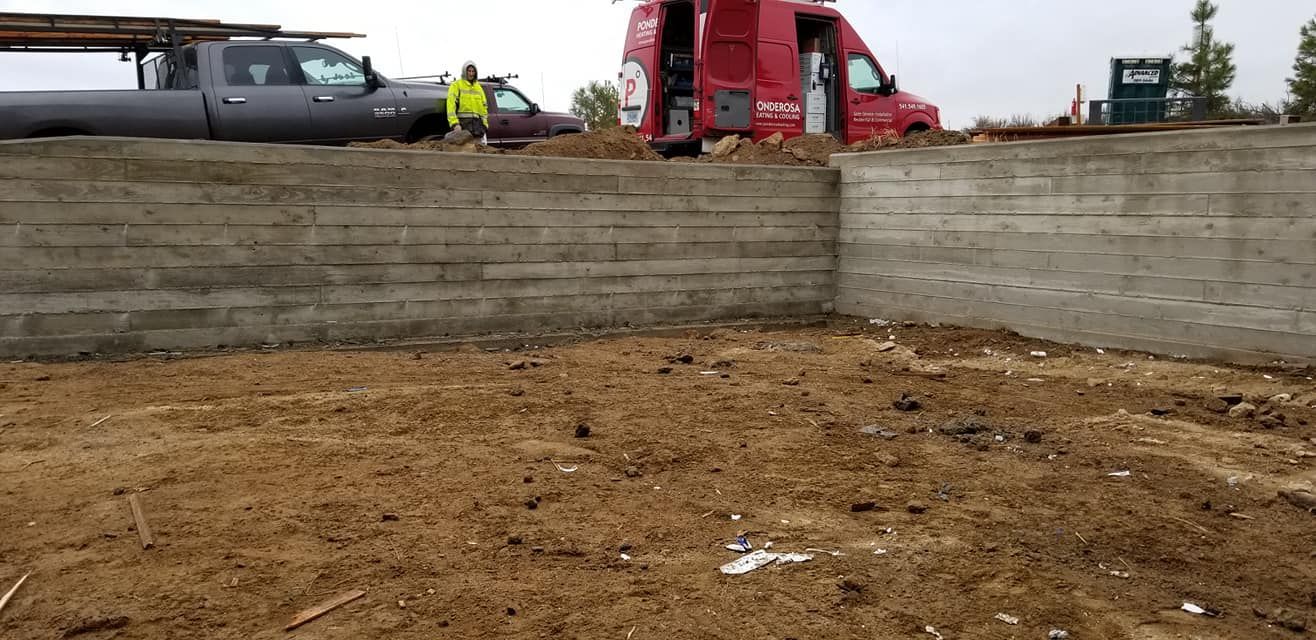 Construction site with concrete retaining wall, dirt, a truck, and workers.