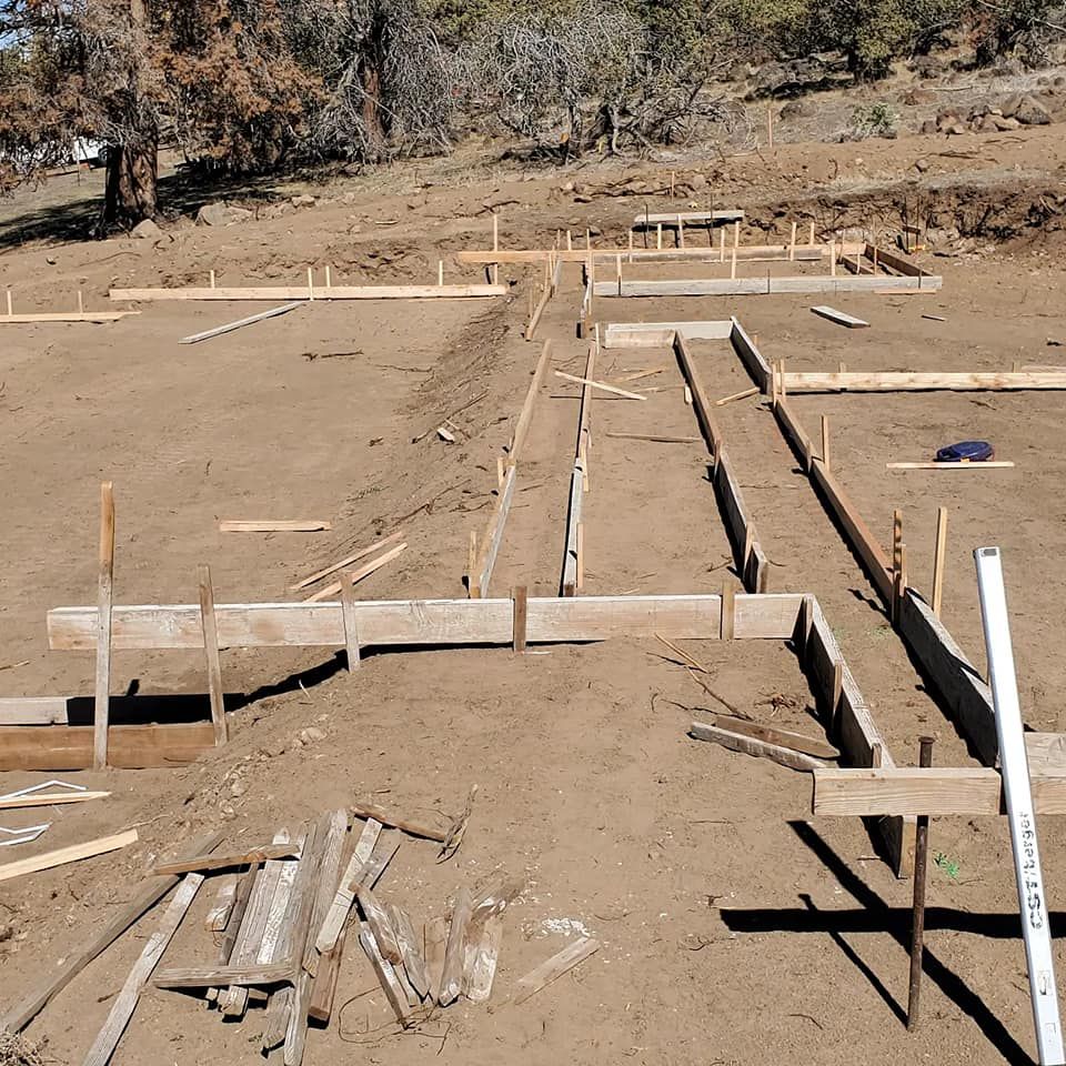Wooden forms set in dirt for pouring a concrete foundation, outdoors.