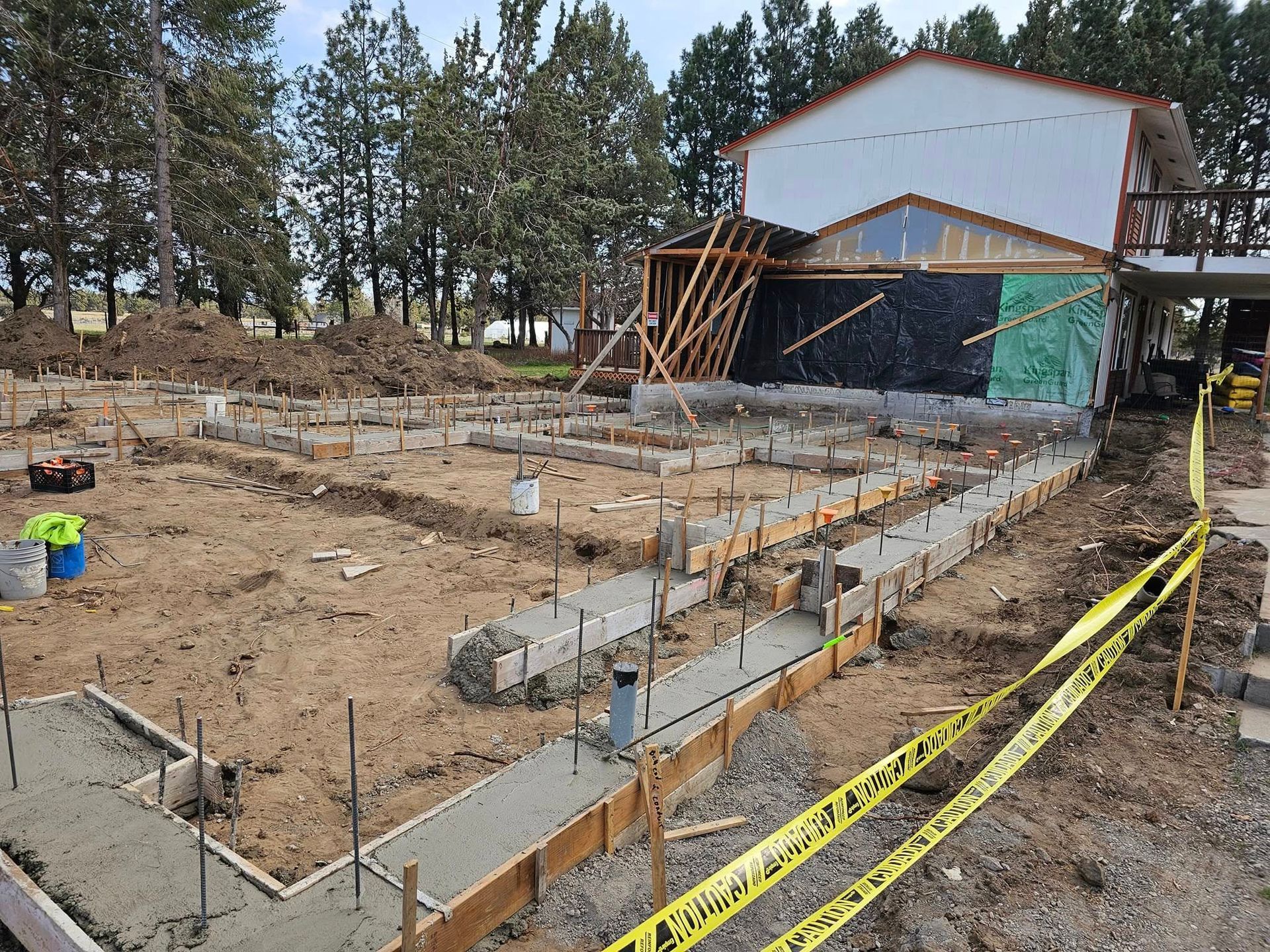 Construction site with concrete foundation and partially built building. Yellow caution tape in foreground.