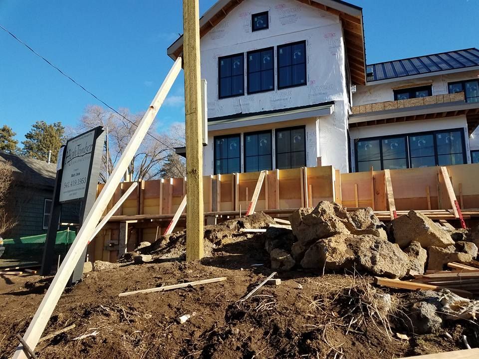 Construction site: house under construction with wood framework, dirt, and rocks.
