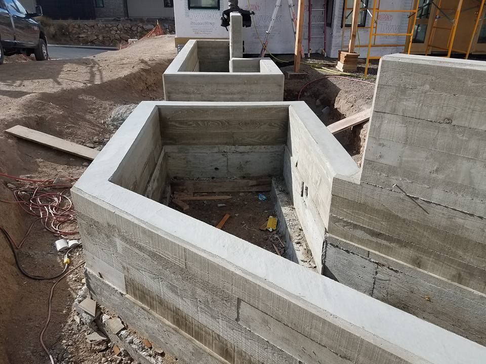 Concrete foundation of a building under construction; gray walls, dirt, and a small debris.