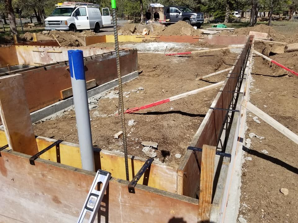 Construction site with wood forms for concrete foundation, rebar, and a pipe.
