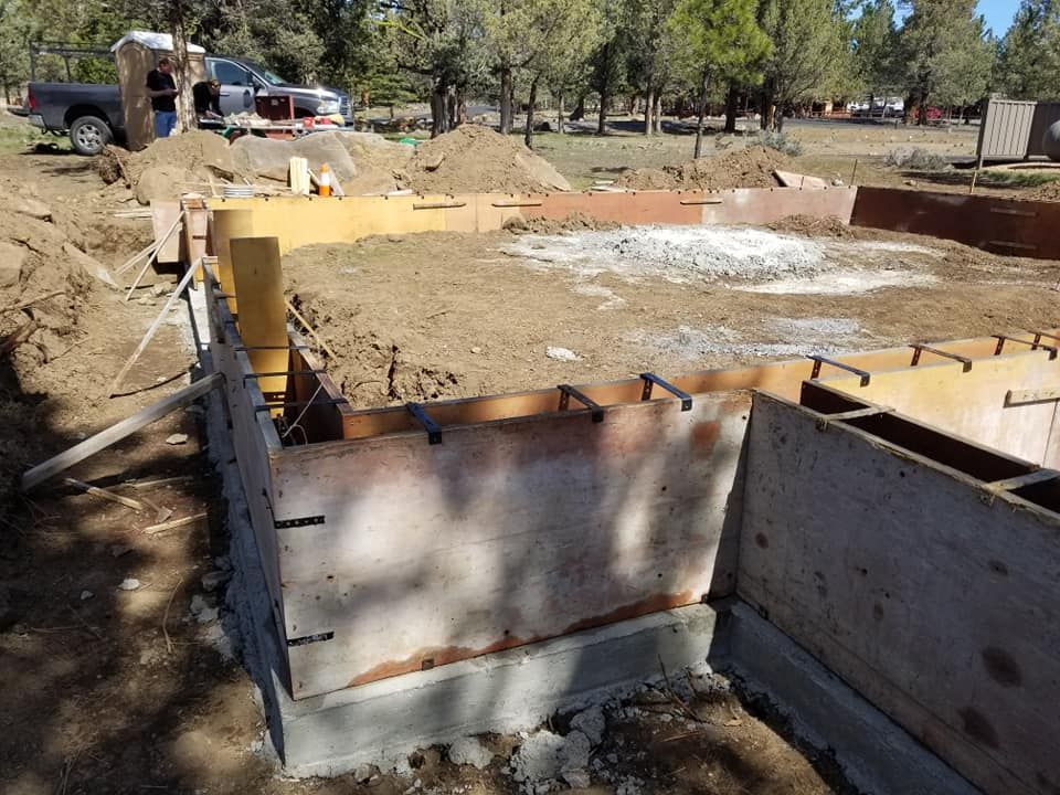 Foundation construction: Wooden forms, concrete blocks, and rebar for a building in an outdoor setting.