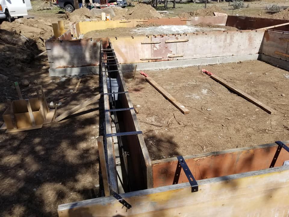 Wooden forms for a foundation. Steel reinforcing bars are in place. Dirt ground.