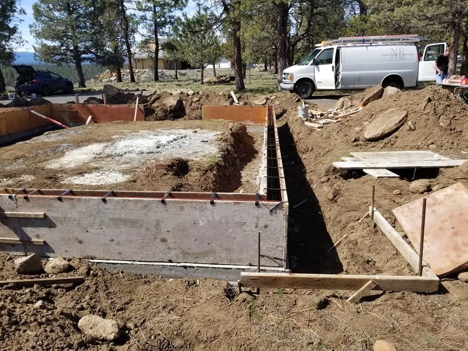 Concrete foundation construction site with forms, earth, and a white van.