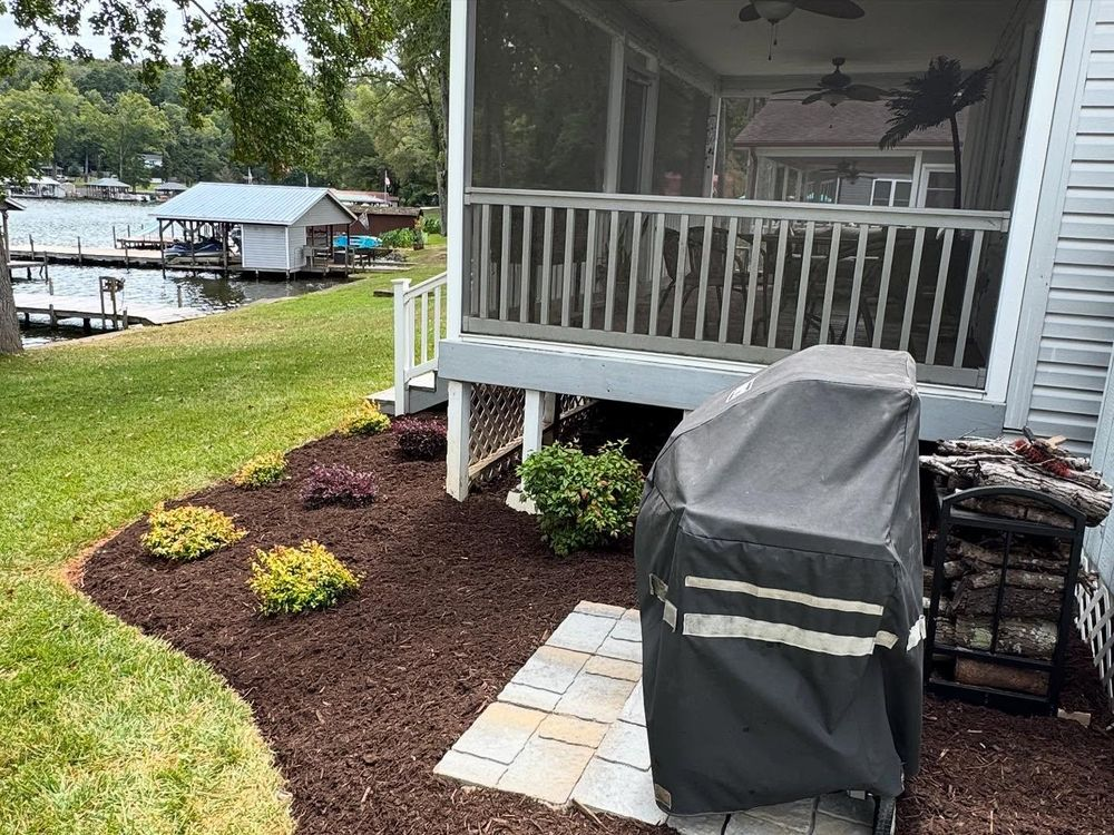 Lakeside backyard with a screened porch, grill, and mulch flower bed.