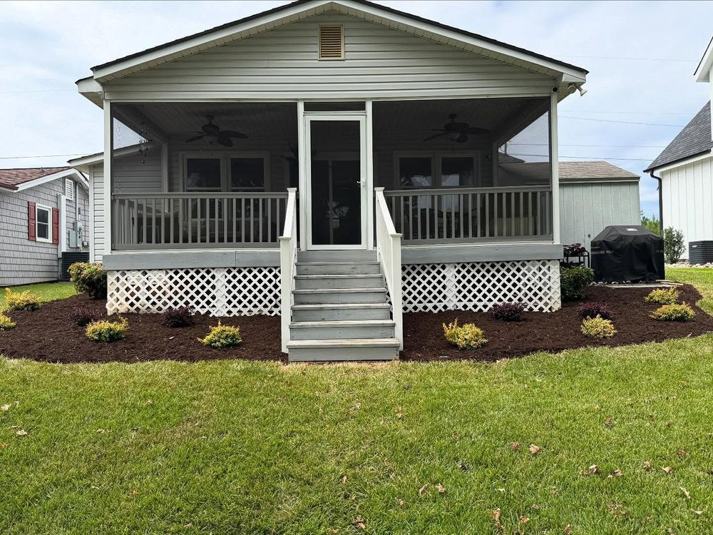 A gray house with a screened porch, wooden steps, and a landscaped yard.
