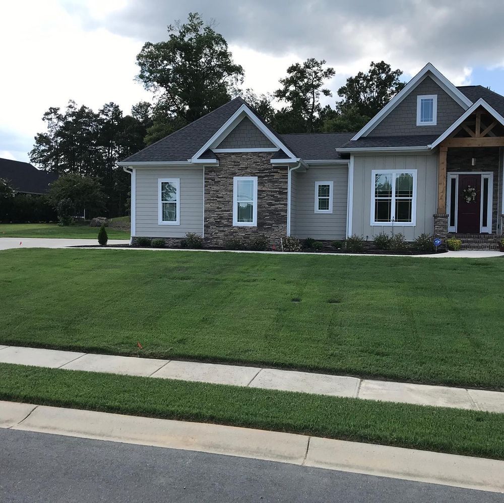 A house with a well-manicured lawn and a gray, blue-sky background.