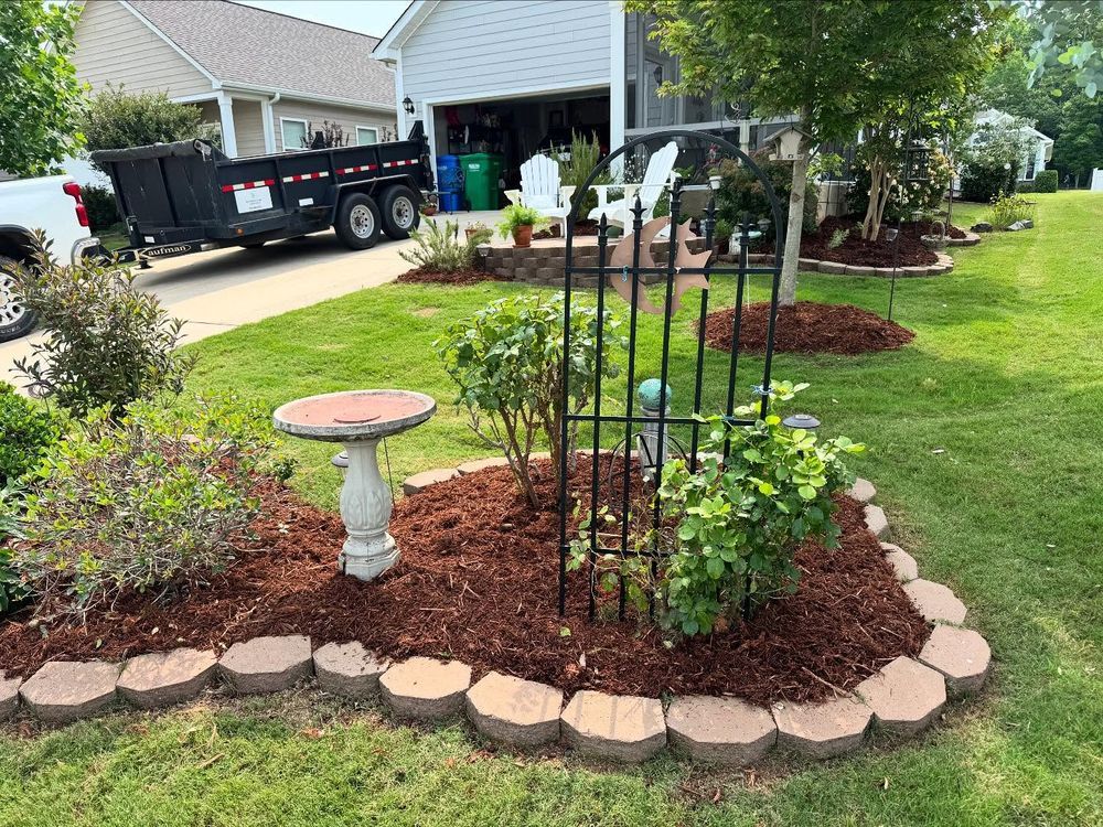 Landscaped yard with fresh mulch and edging, a birdbath, and a trailer.