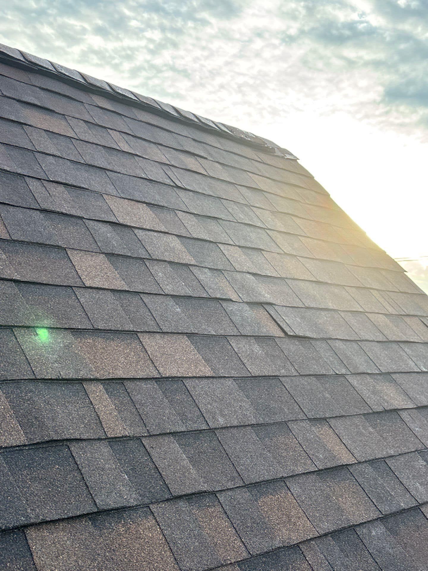 The sun is shining through the clouds on the roof of a house.