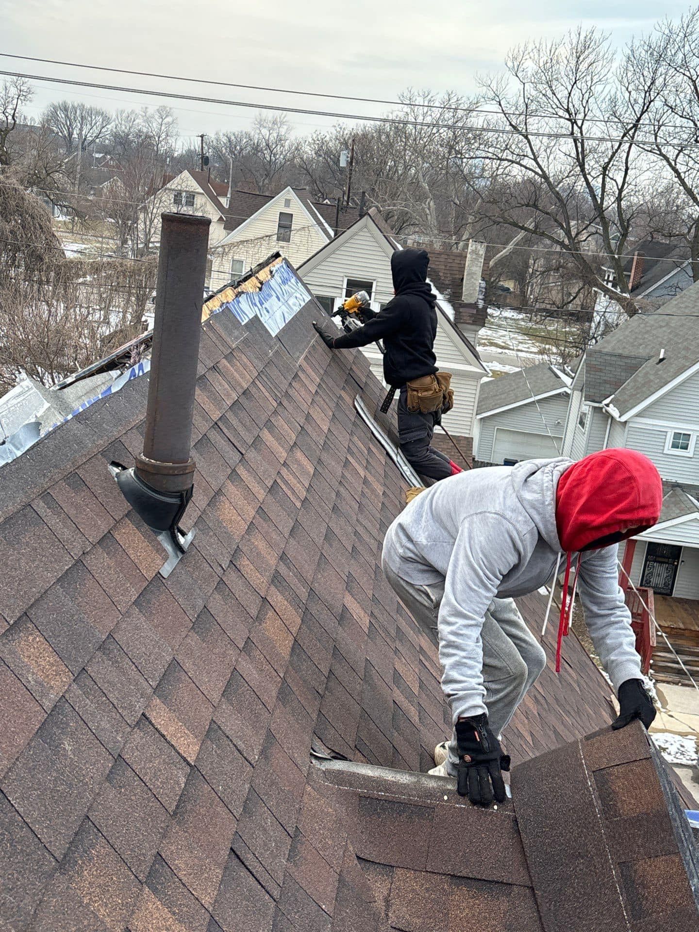 Two men are working on the roof of a house.
