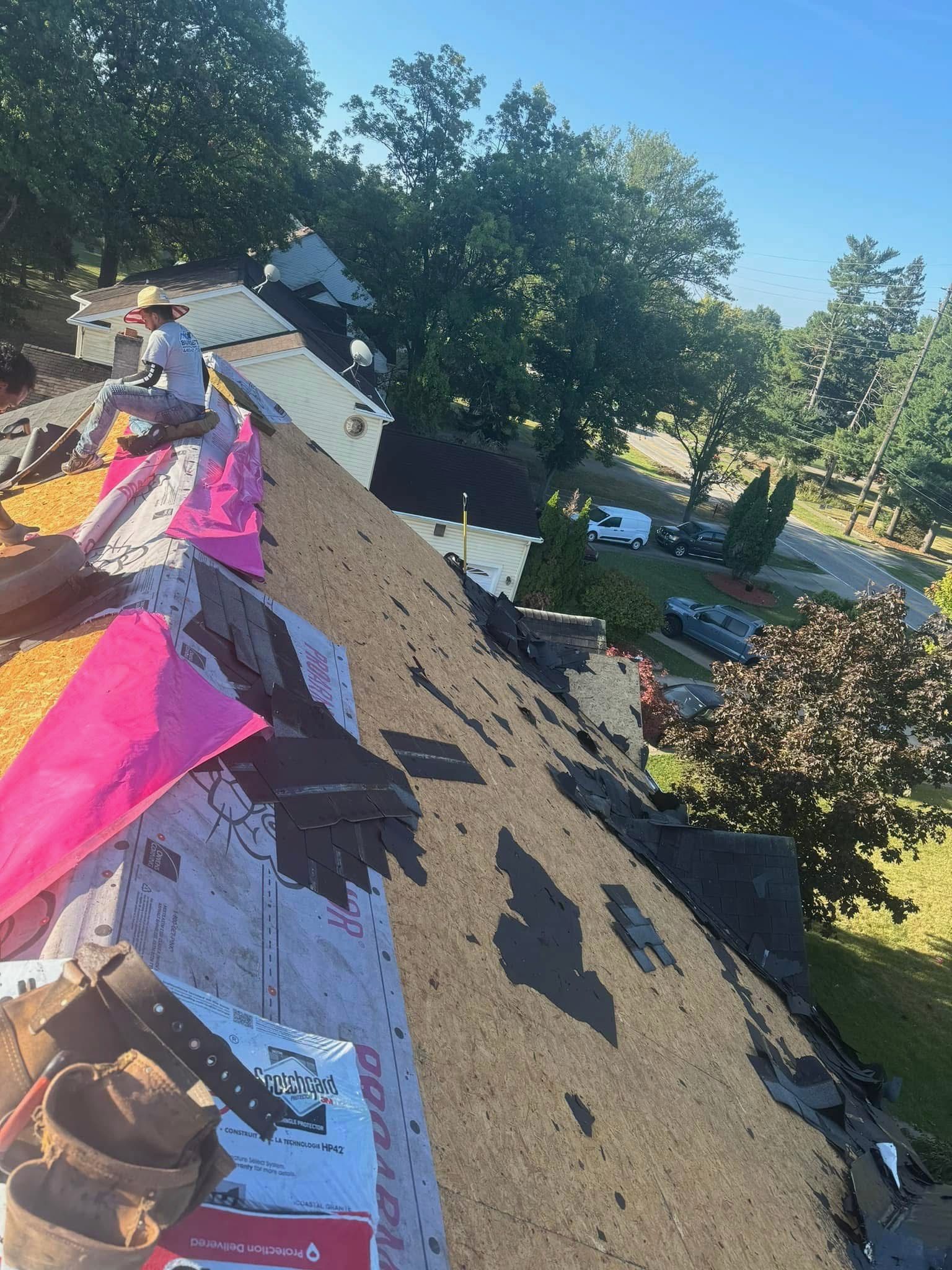 Two men are standing on ladders working on the roof of a house.