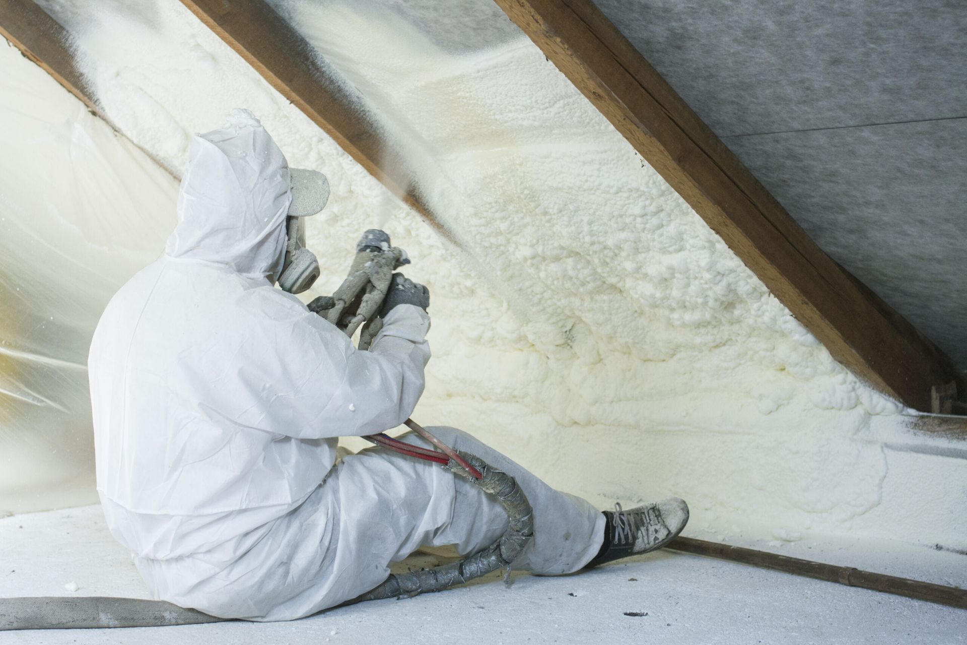 Contractor spraying under roof with spray foam insulation