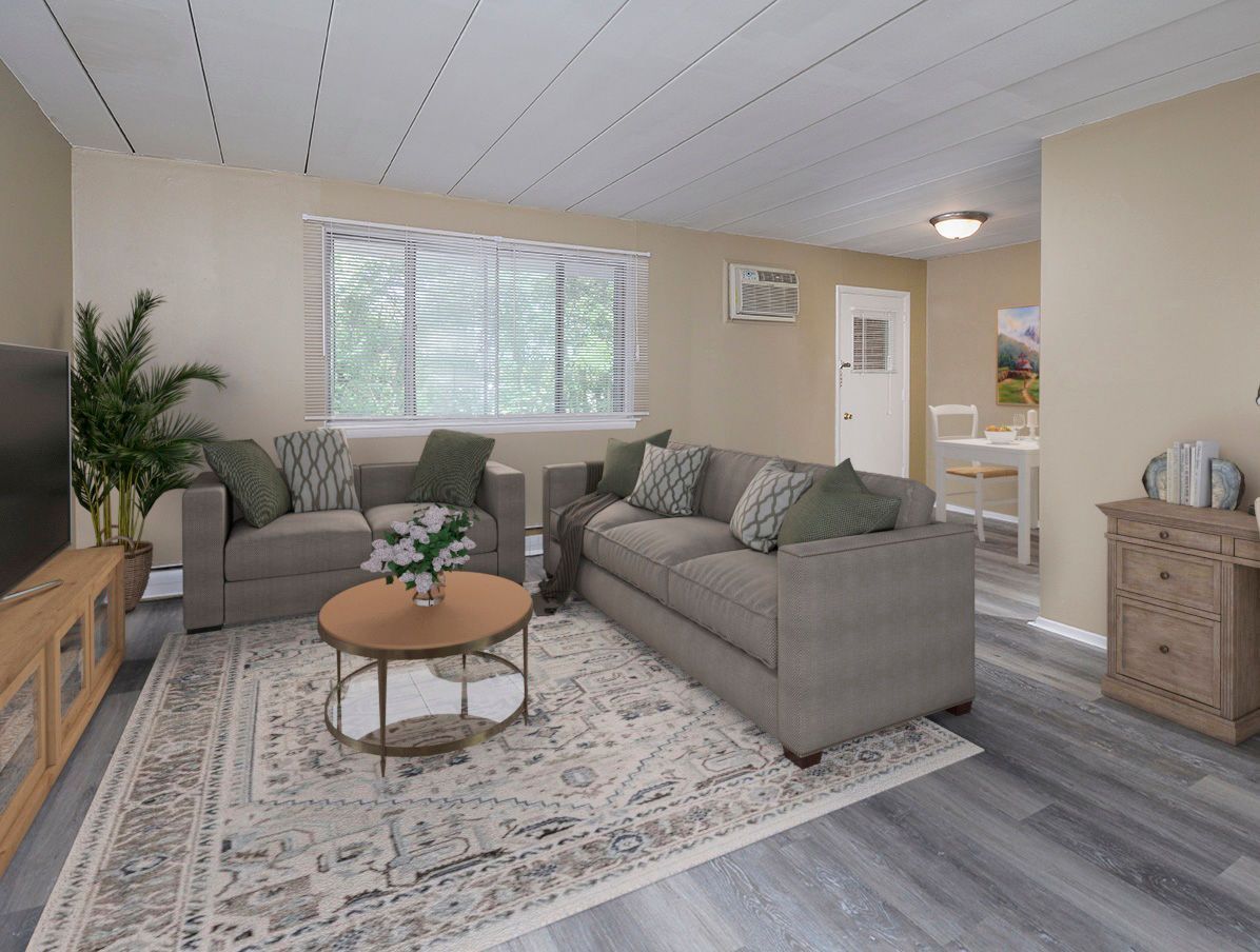 Living room with two gray sofas, a round coffee table, patterned rug, and a window.