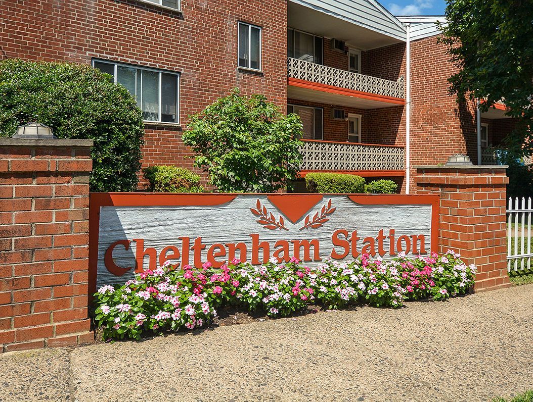 Exterior brick sign for Cheltenham Station with flower beds.