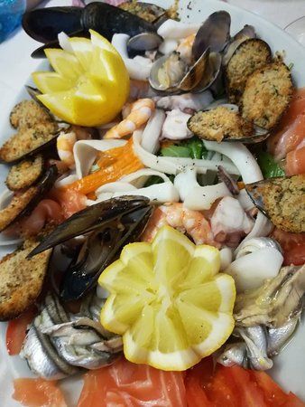 Piatto di frutti di mare: cozze, vongole, gamberi, calamari, spicchi di limone e salmone.