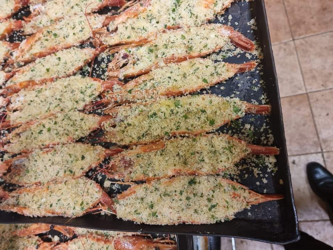 Vassoio di gamberi impanati, pronti per essere infornati.