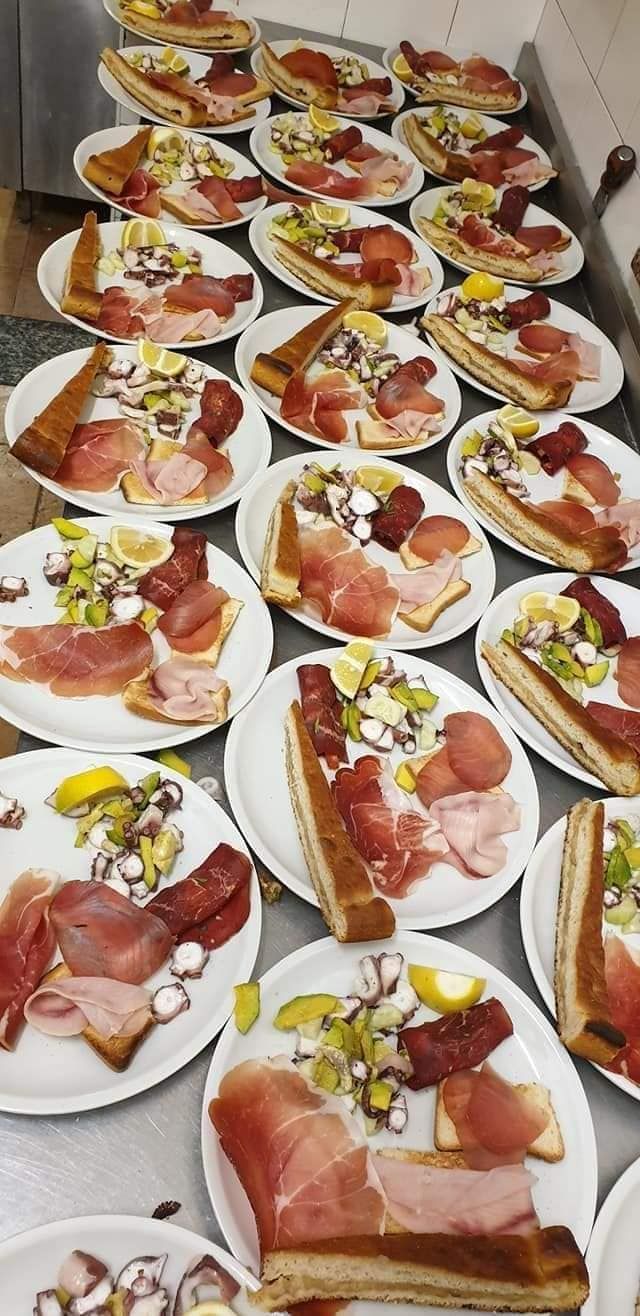 Piatti di cibo, tra cui pane, salumi e un'insalata tritata, disposti su una superficie.