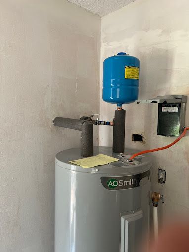 A water heater is sitting in a corner of a room next to a wall.