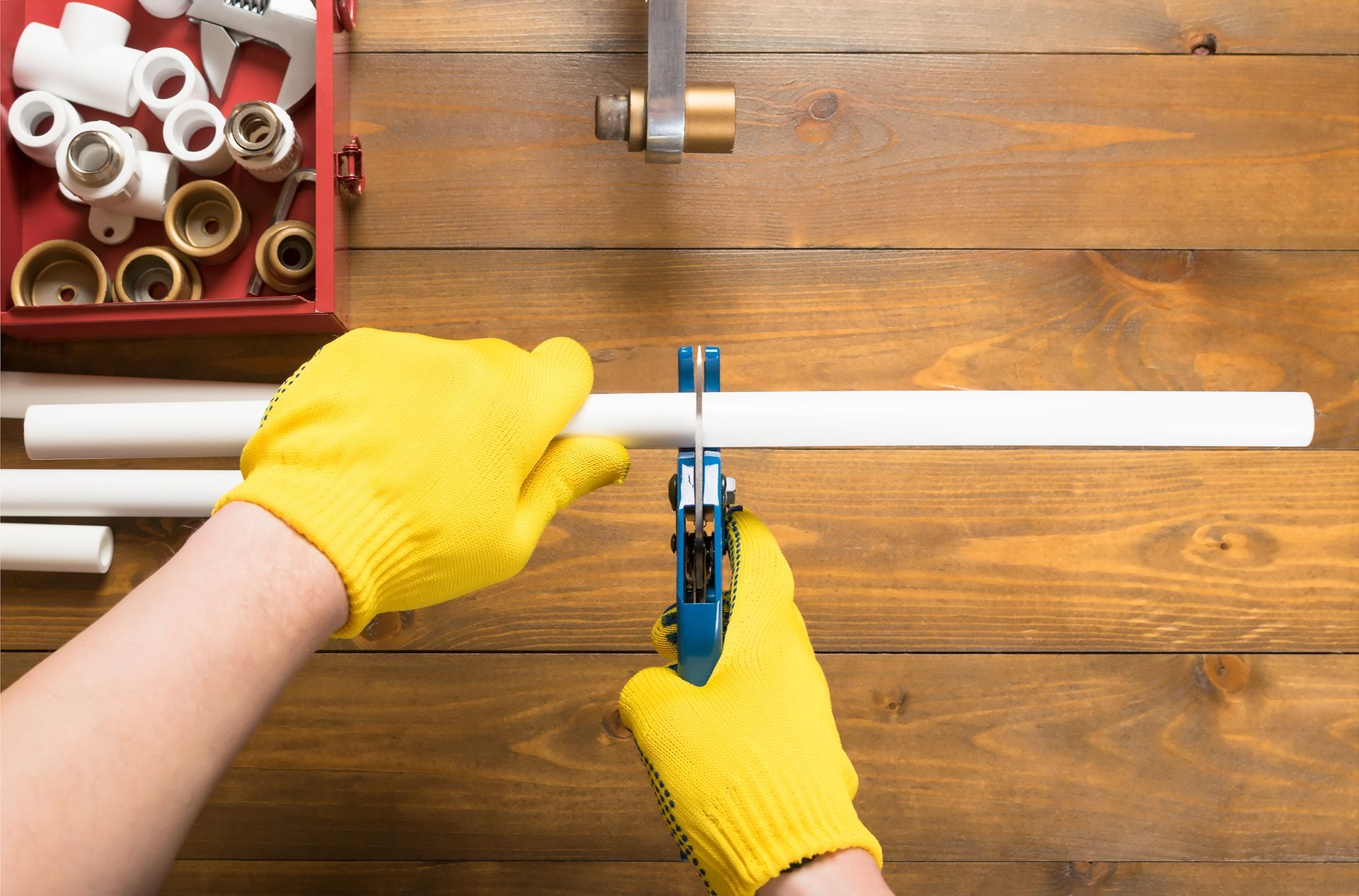 Close-up of a Roto-Rooter Sewer & Drain Cleaning worker’s hand Cutting plastic pipe with scissors