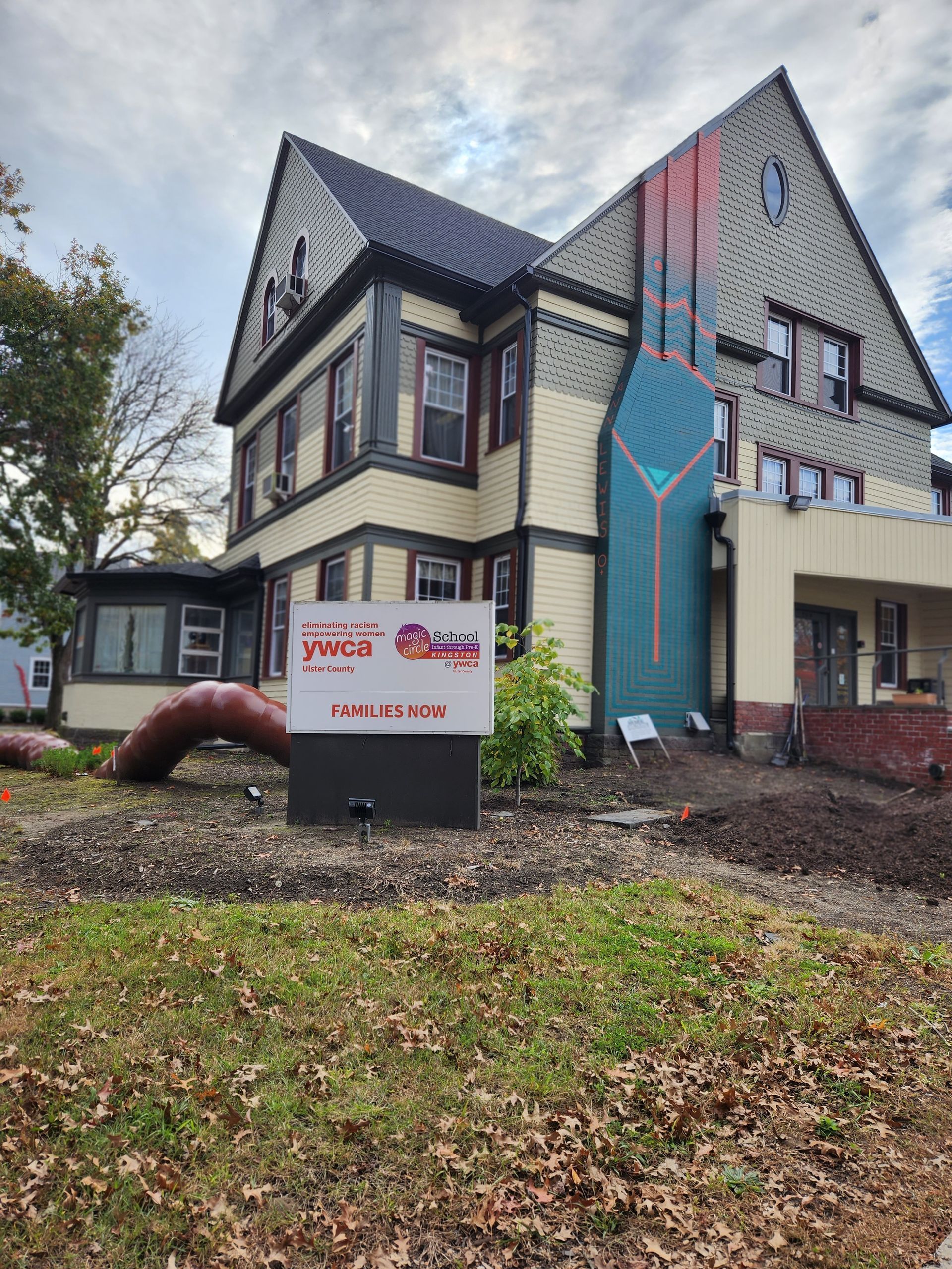 Sign in front of a multi-story building, painted with a large bottle mural.