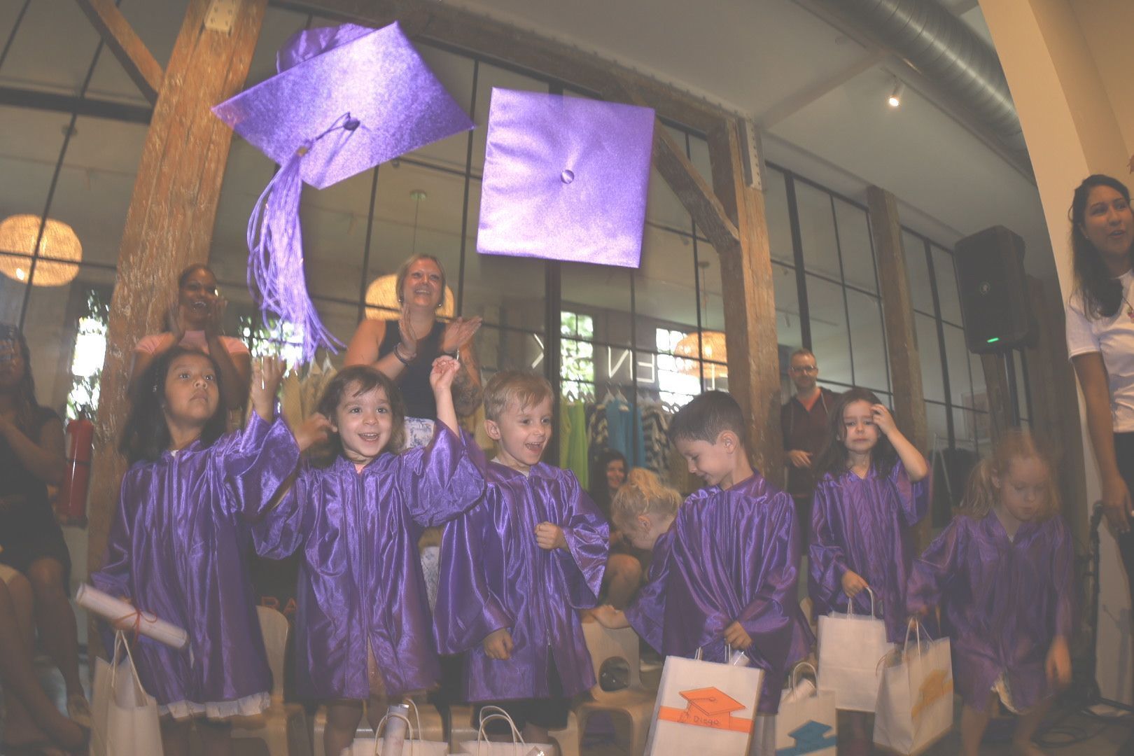 Children in purple graduation gowns toss caps in the air.