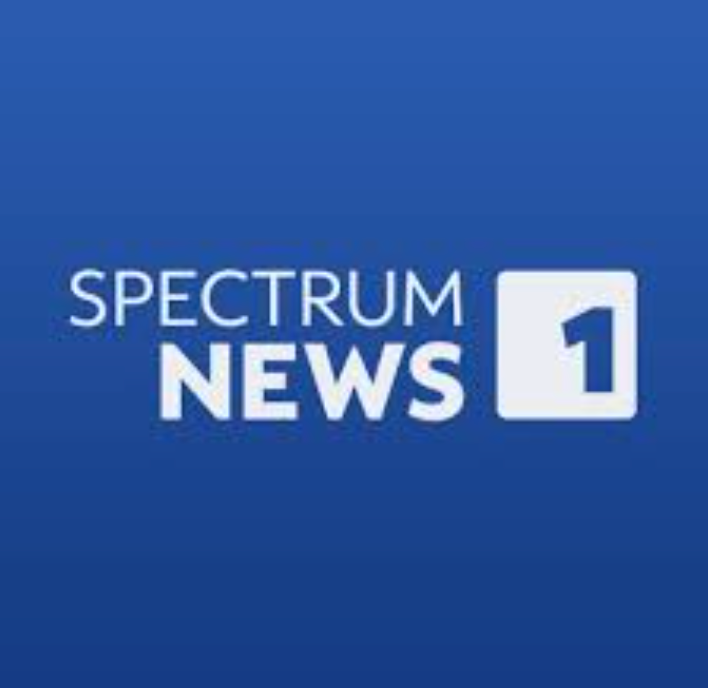 Spectrum News 1 logo: White text and a white box with a 