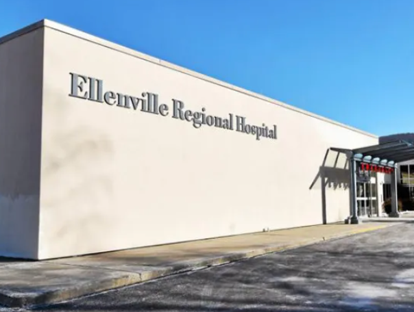 Exterior of Ellenville Regional Hospital, light tan building, with entrance under a small awning.