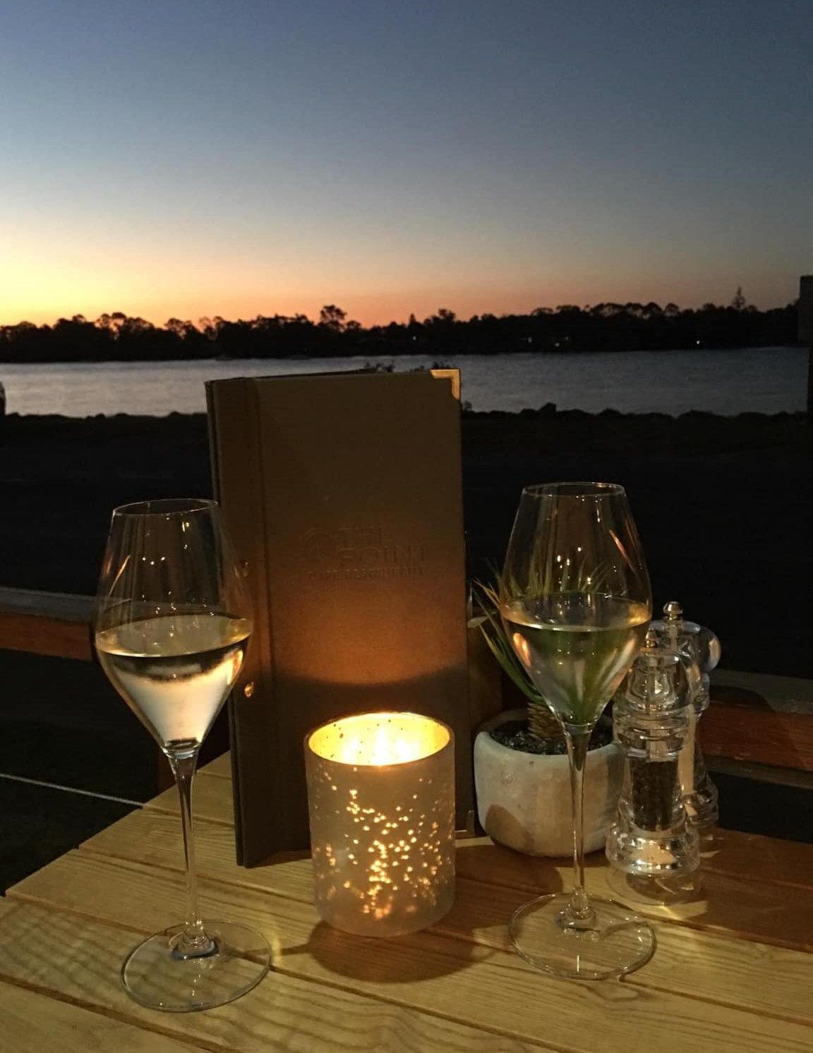 Two Glasses of Wine and A Candle on A Table with A Sunset in The Background — The Point Cafe Restaurant in Port Macquarie, NSW