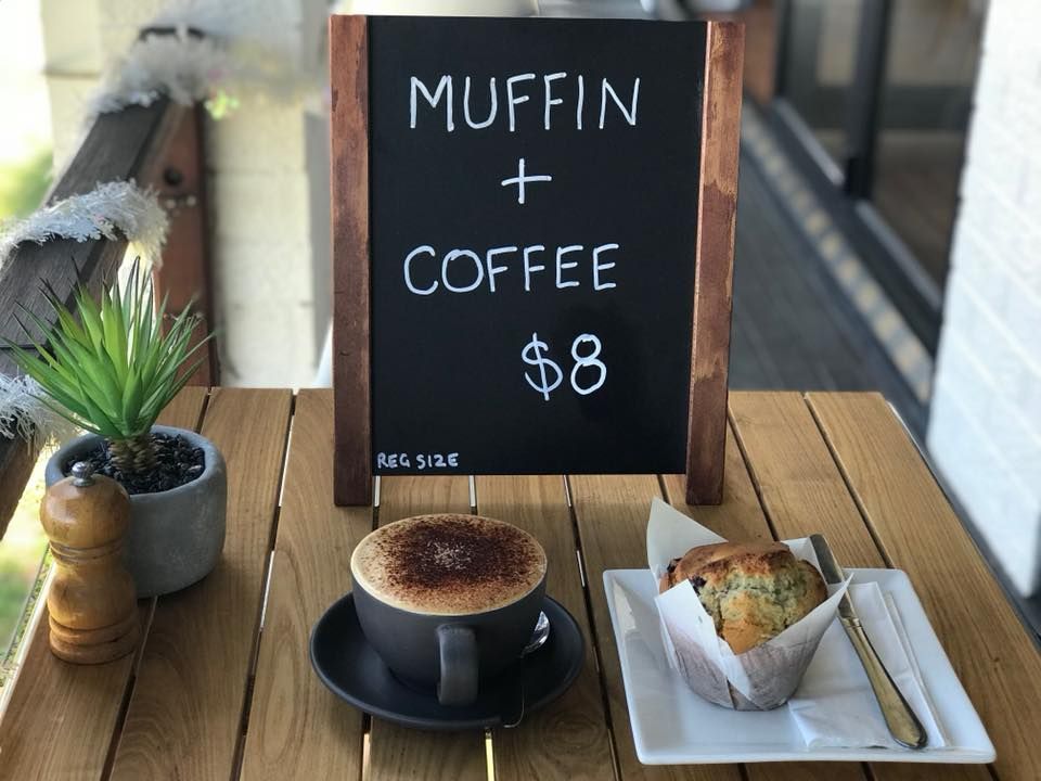 A Wooden Table with A Muffin and A Cup of Coffee on It — The Point Cafe Restaurant in Port Macquarie, NSW