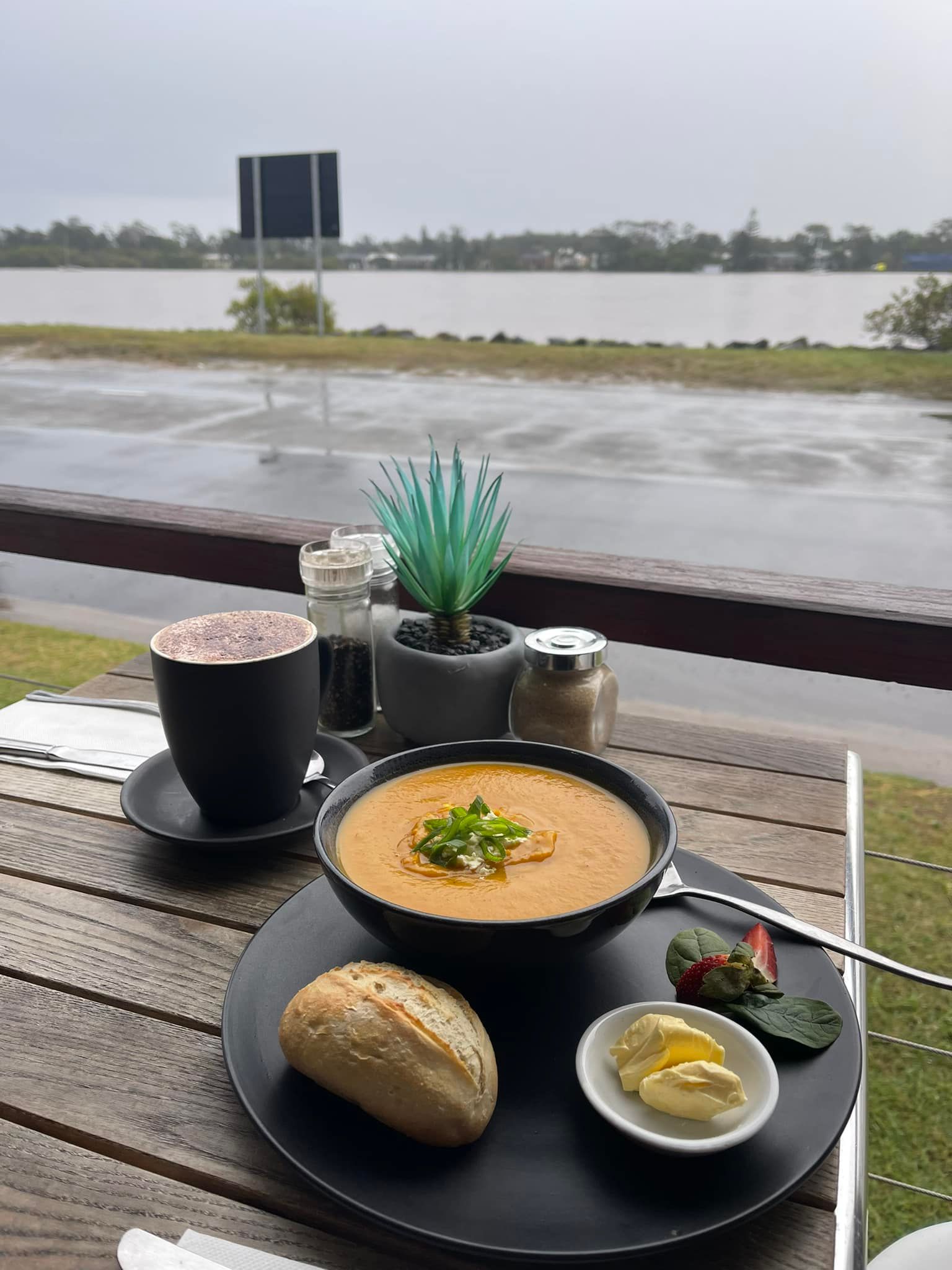 A Bowl of Soup Is Sitting on A Wooden Table Next to A Cup of Coffee — The Point Cafe Restaurant in Port Macquarie, NSW