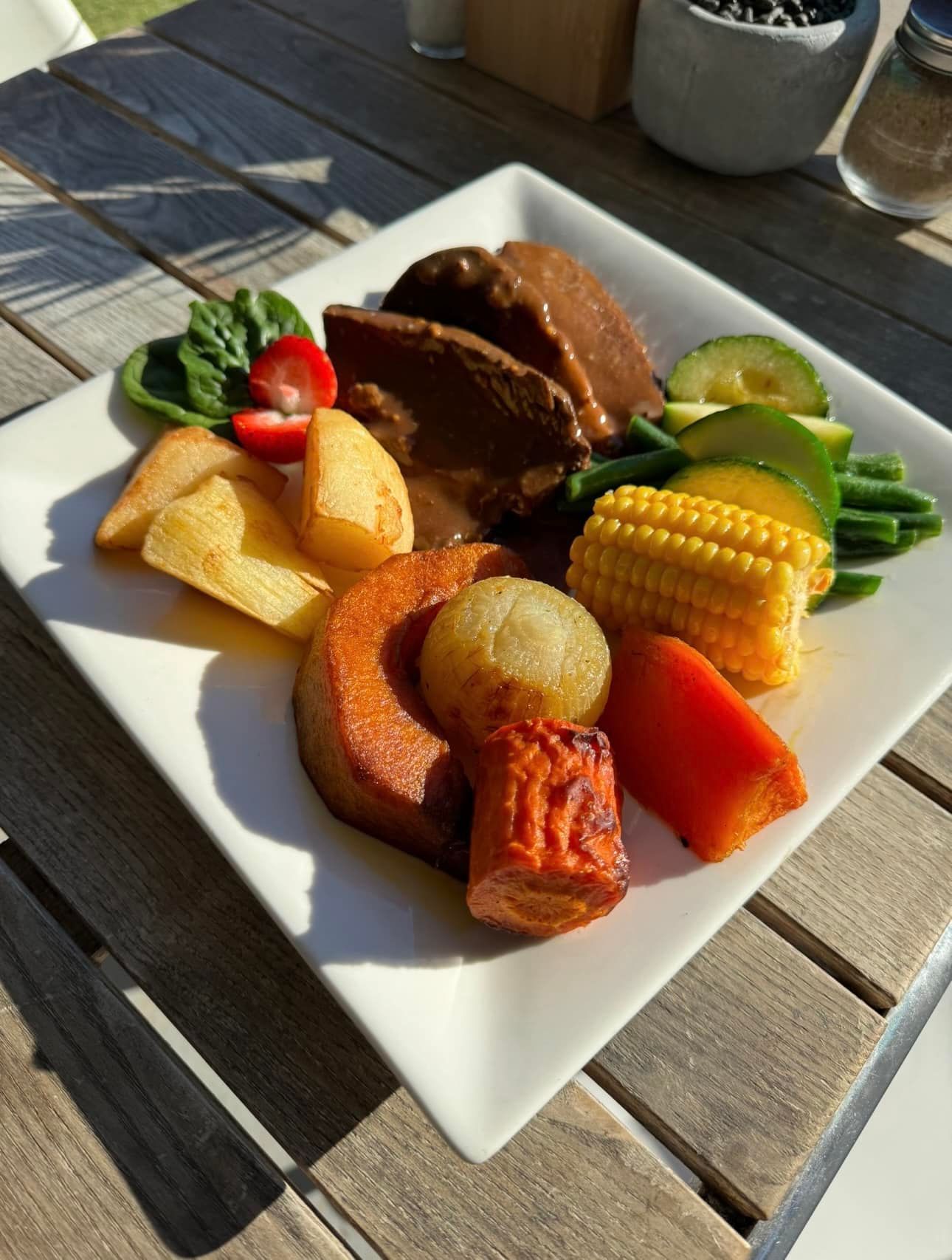A White Plate Topped with Meat and Vegetables on A Wooden Table — The Point Cafe Restaurant in Port Macquarie, NSW