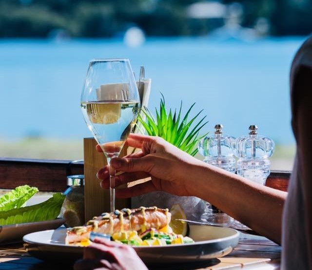 A Person Is Sitting at A Table with A Plate of Food and A Glass of Wine — The Point Cafe Restaurant in Port Macquarie, NSW