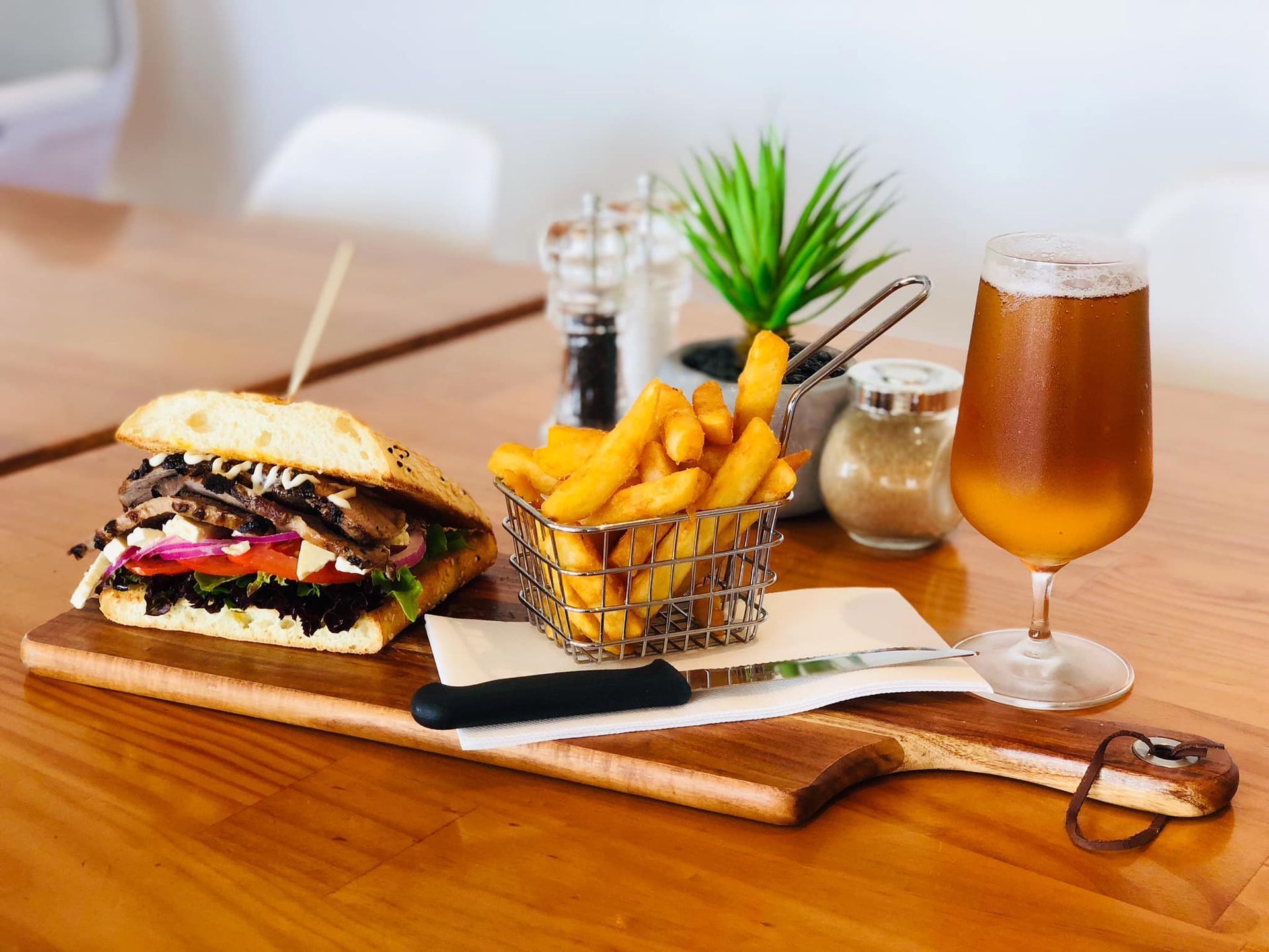 A Sandwich, French Fries, and A Glass of Beer on A Wooden Table — The Point Cafe Restaurant in Port Macquarie, NSW
