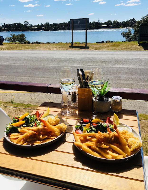 Two Plates of Food on A Table with A View of A Lake — The Point Cafe Restaurant in Port Macquarie, NSW