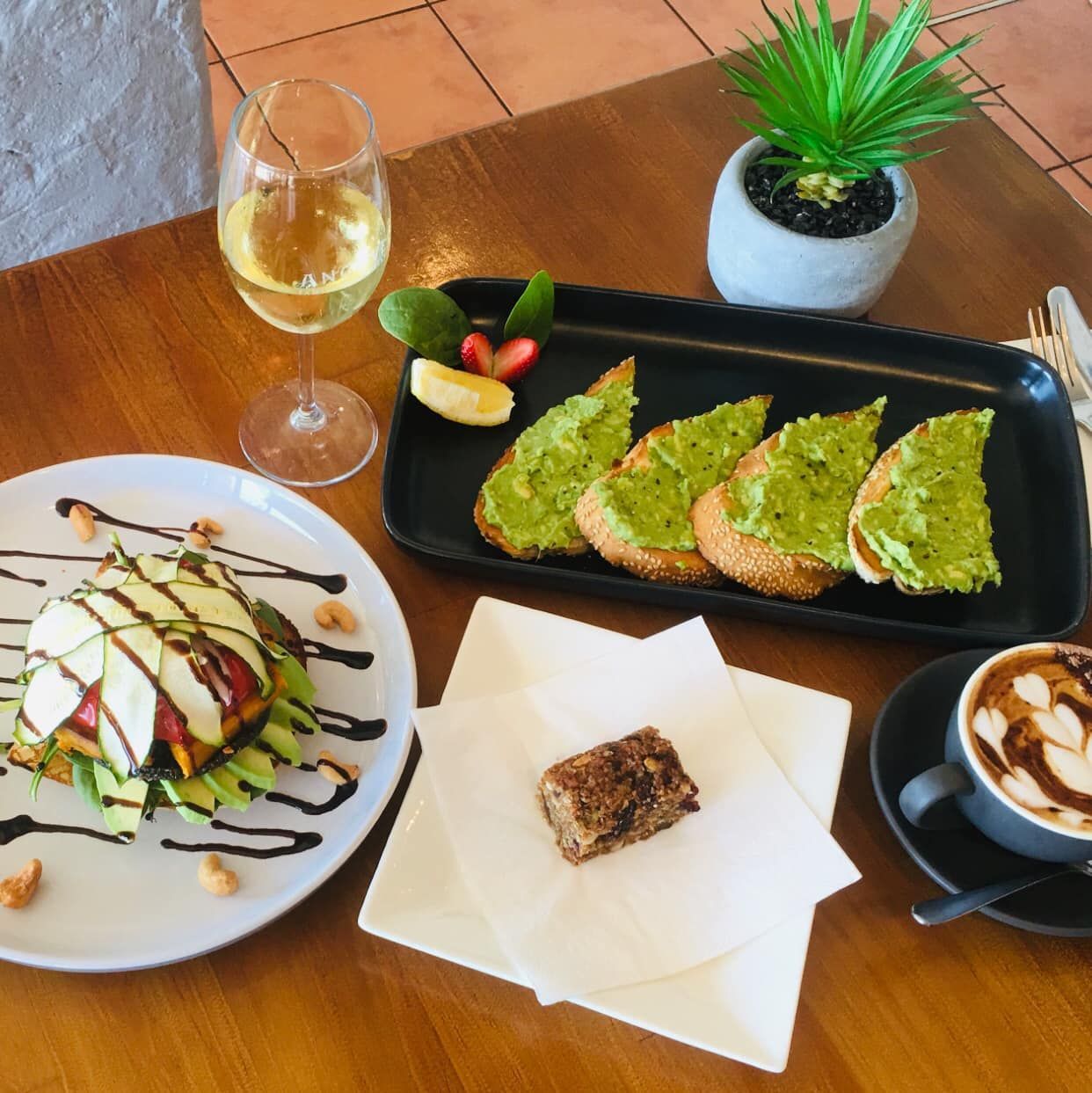 A Table Topped with Plates of Food and A Glass of Wine — The Point Cafe Restaurant in Port Macquarie, NSW
