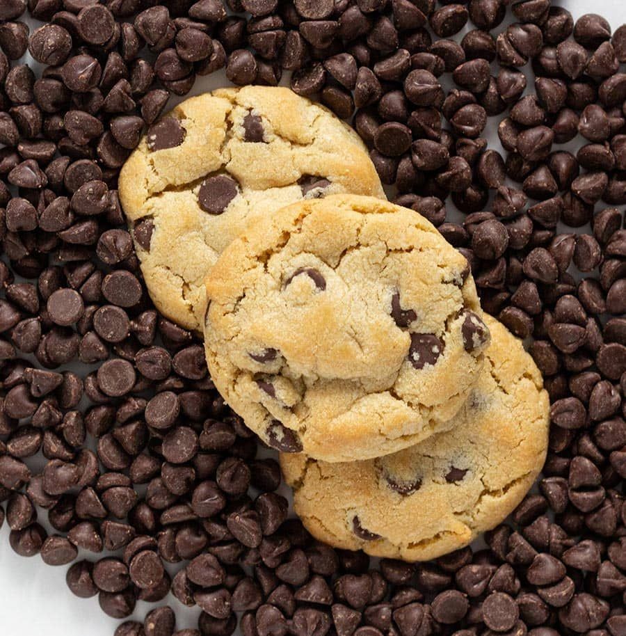 Three chocolate chip cookies atop a bed of chocolate chips.