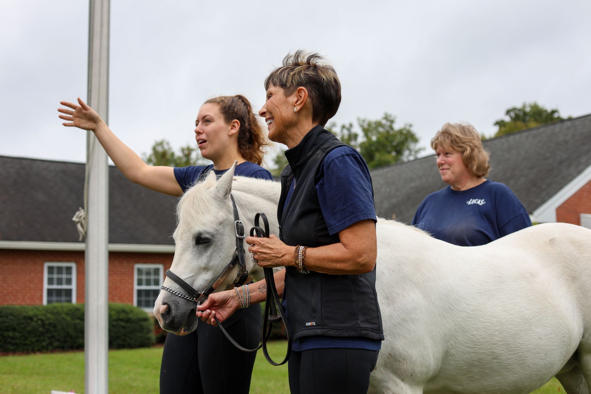 3 riding instructors next to a white horse