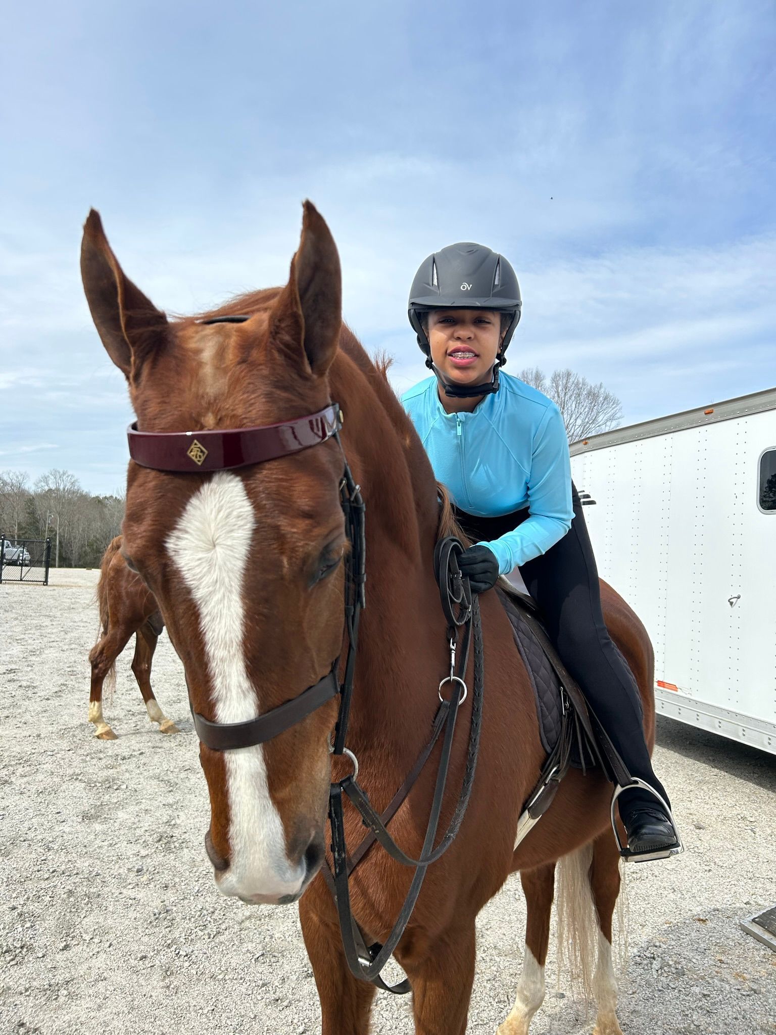 a teenage girl wearing a riding helmet riding a brown horse with white on its face