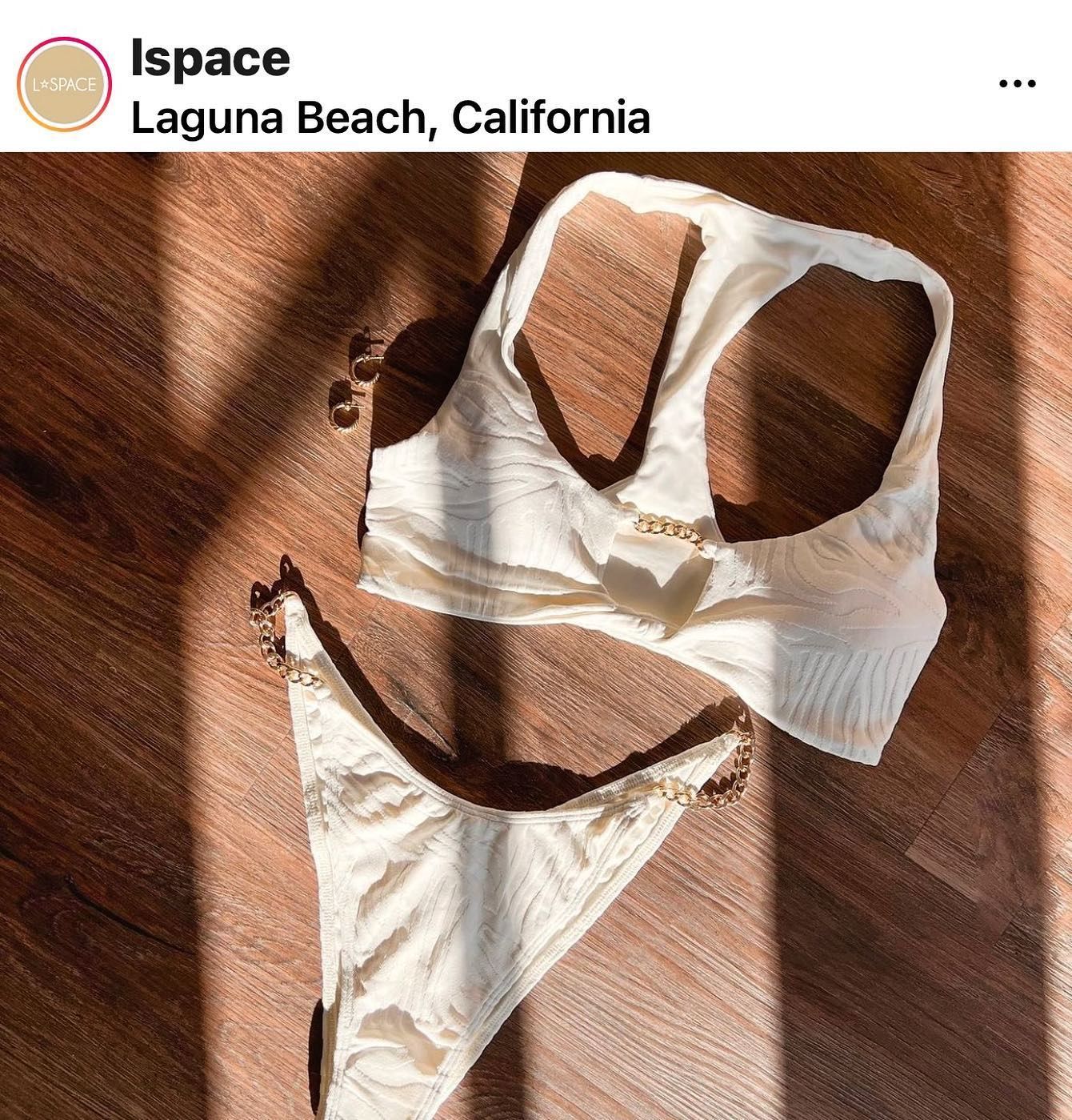 Cream-colored bikini with gold chain accents on a wood surface in Laguna Beach, California.