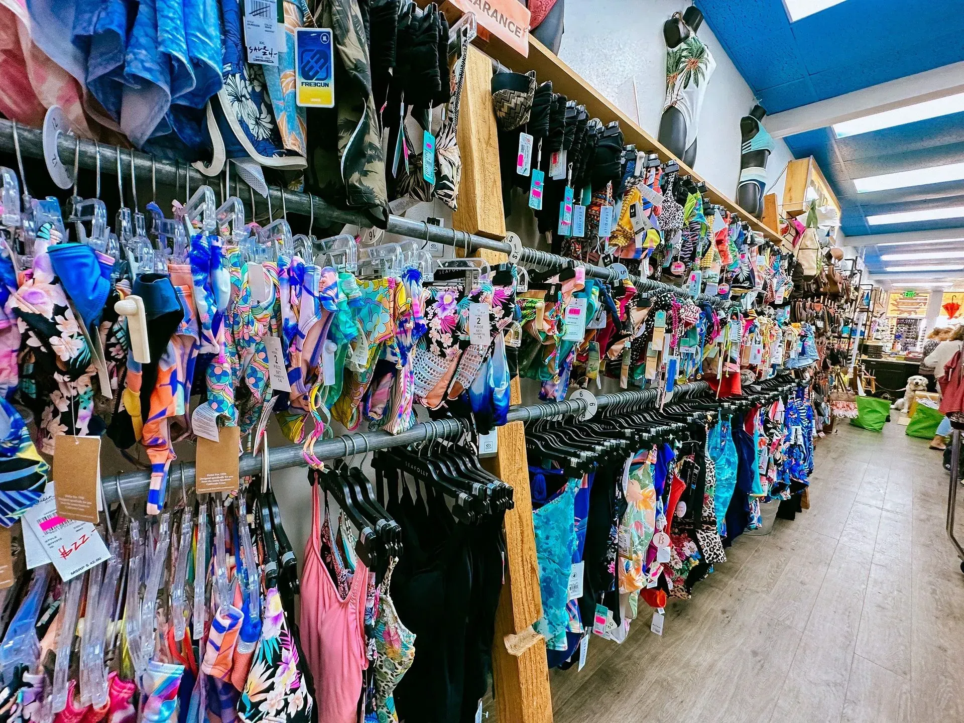 Swimsuits hanging on racks in a brightly lit retail store.