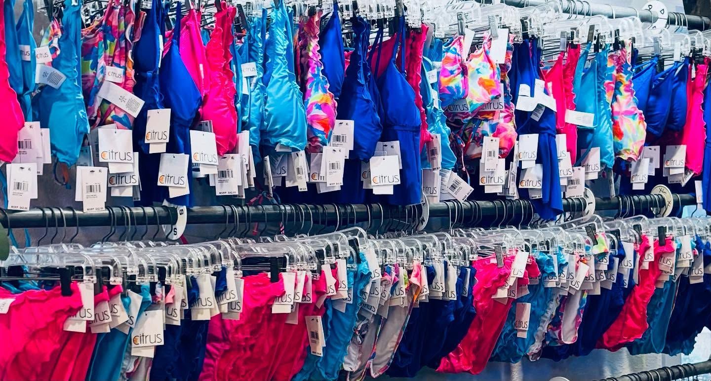Swimsuits hanging on racks; mostly blue, pink, and patterned.