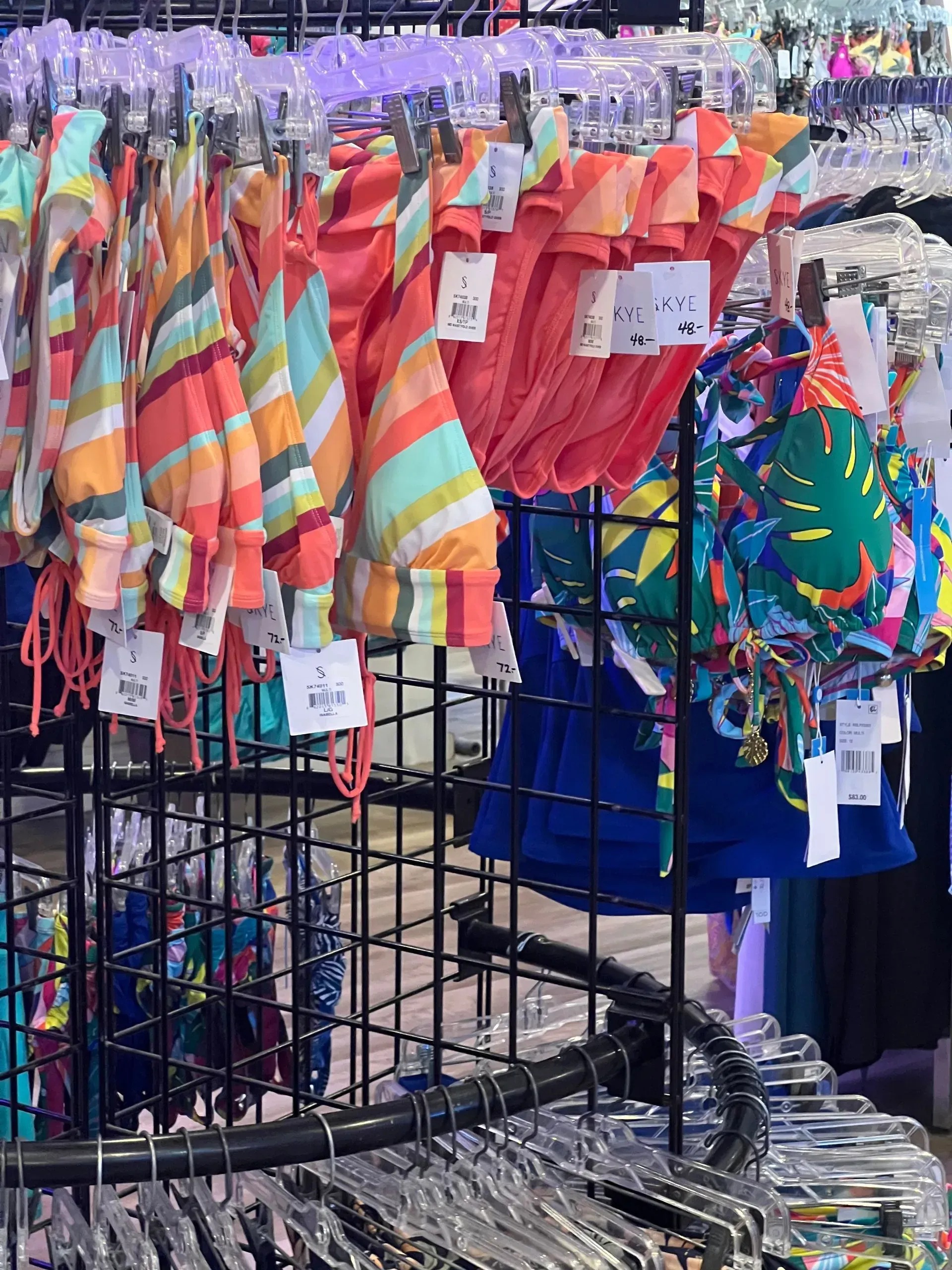 Swimsuits on display racks; various colors and patterns.
