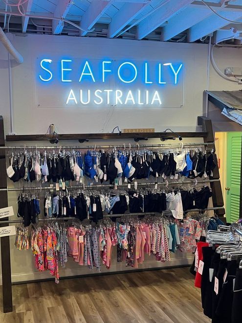 Seafolly Australia store display with swimwear hanging on racks below a neon sign.